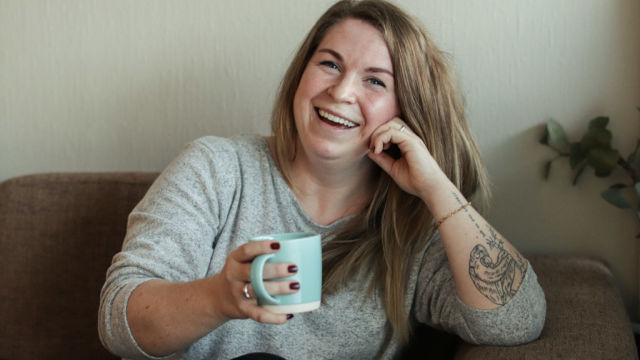 Bilde av Silje Ubostad. Hun sitter i en sofa med en kaffekopp i hånden.